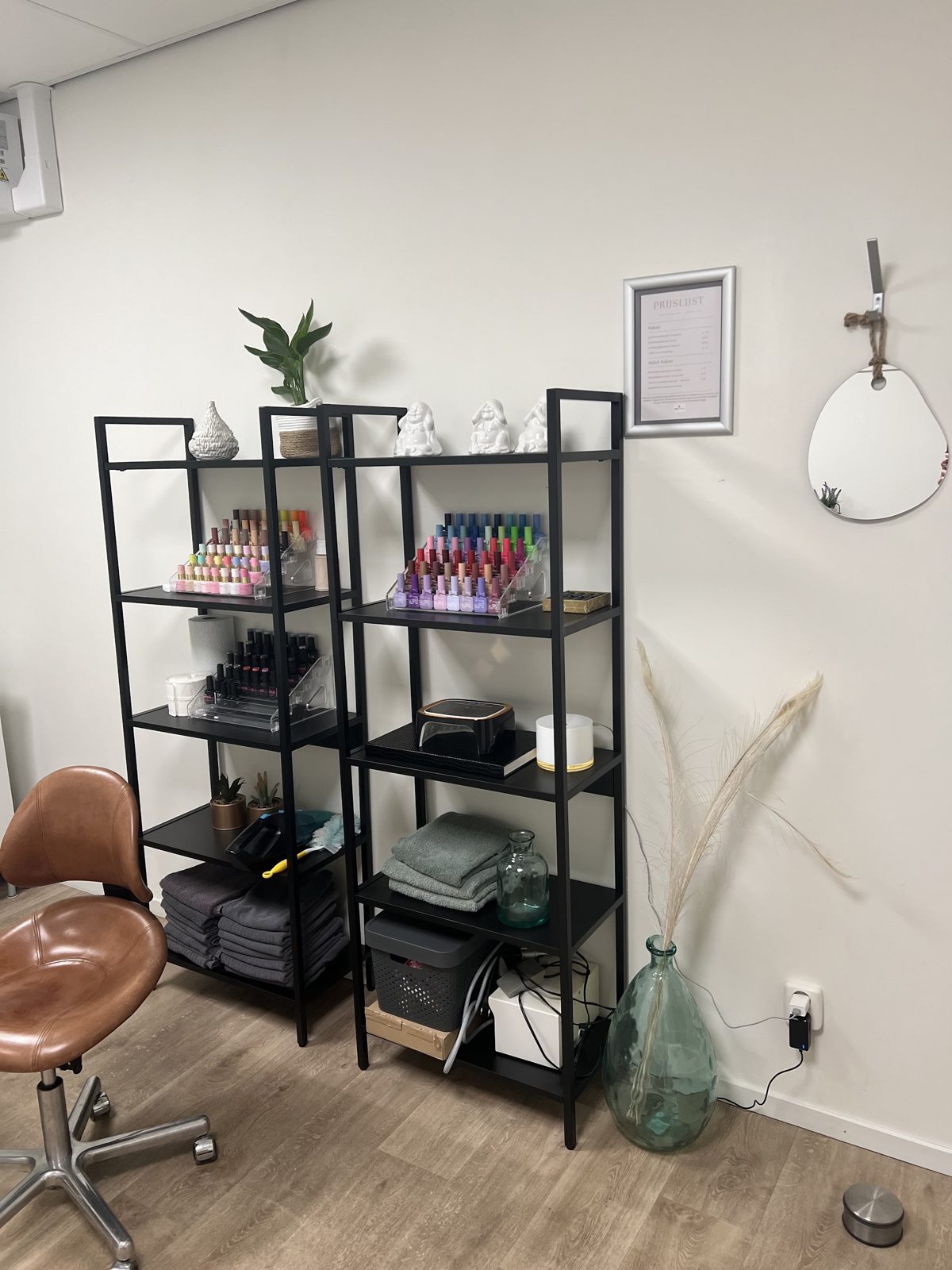 Rekken vol gellakkleuren, handdoeken en planten in de salon