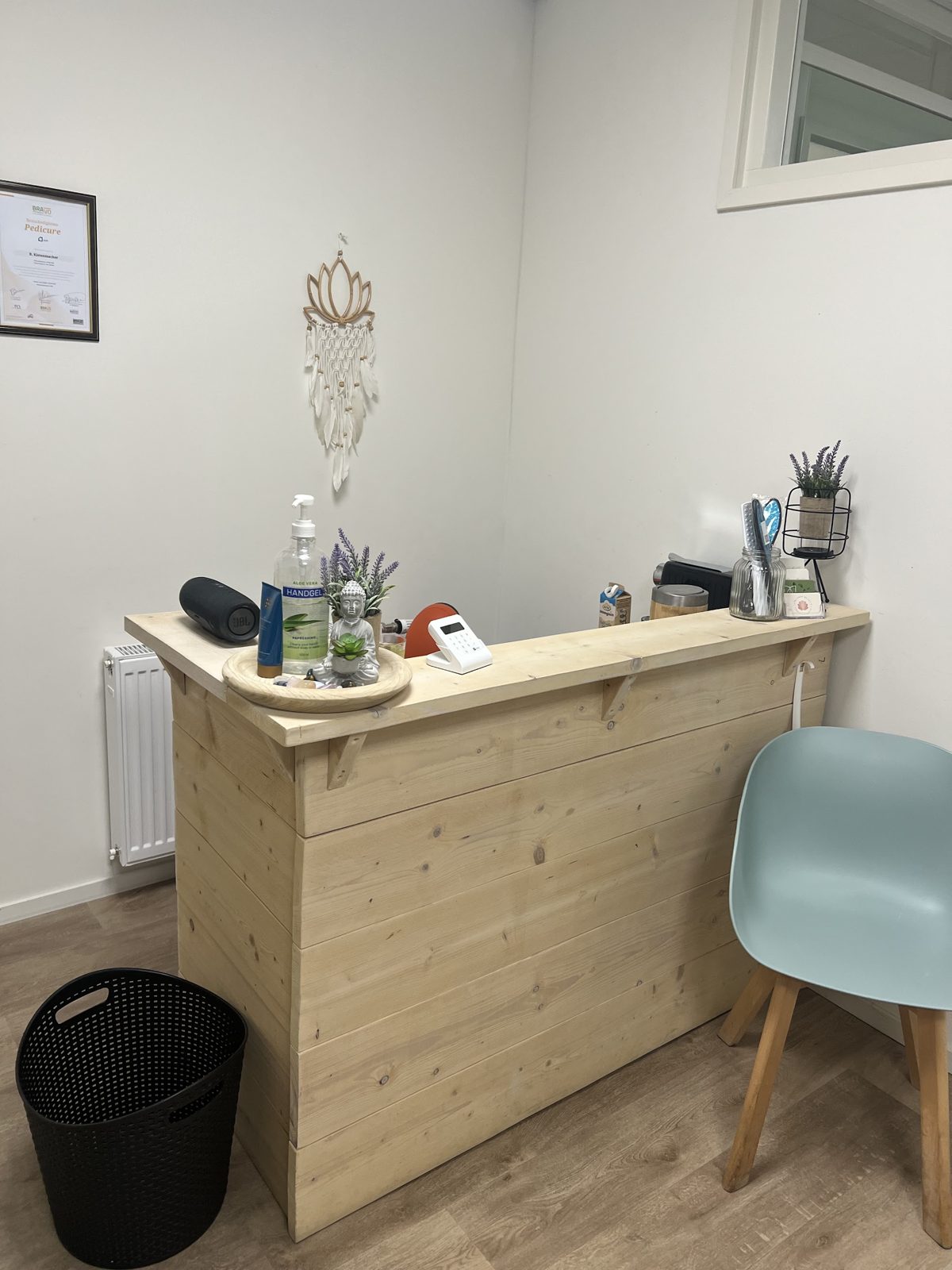 De houten balie van de salon met lavendel, een lotus-wandhanger en het ingelijste diploma